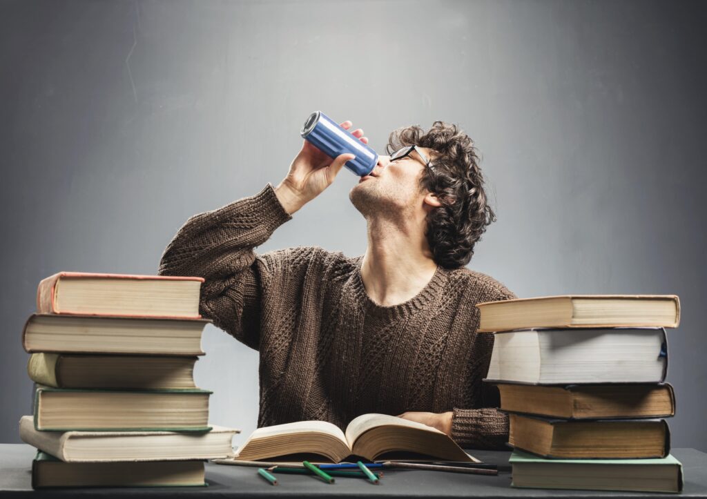 مرد جوانی در حال مطالعه و نوشیدن نوشیدنی انرژی زا.